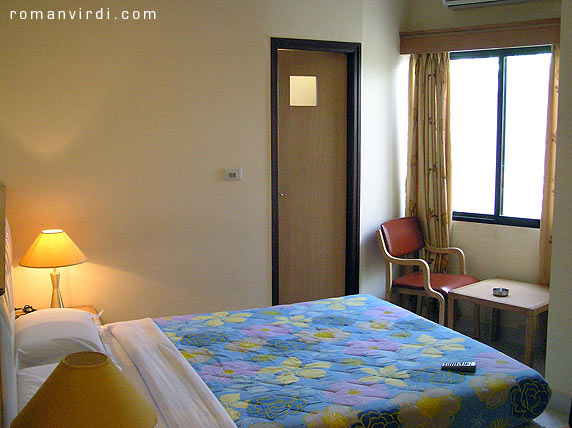 Hotel Empire International, Bangalore, Room 403, a "deluxe double room", on the 4th floor, viewed from the entrance 
corridor. The door ahead leads to the shower/toilet. The spilt a/c is visible 
above the window. The window faces a wall - no outside view available