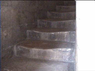The first flight of stairs leaning up the tower are relatively wide. The stairs seem worn unevenly due to the lean of the tower